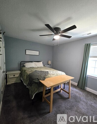 A bedroom with a bed, nightstand, and a ceiling fan.