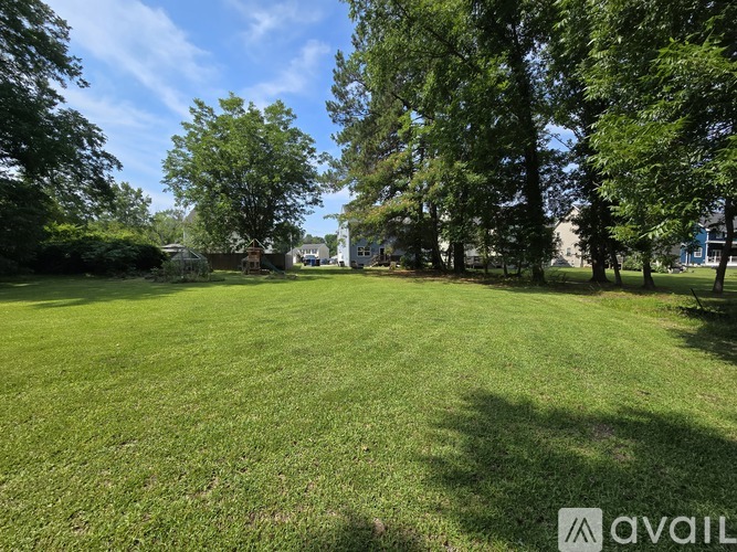 A grassy field with trees and a clear sky.