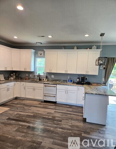 A kitchen with white cabinets and a wooden floor.