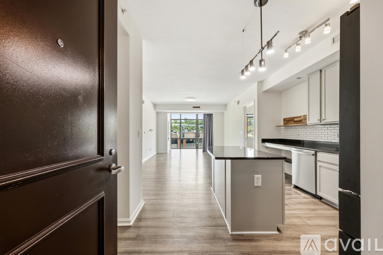 A kitchen with a black refrigerator and wooden floors.