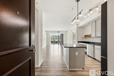 A kitchen with a black refrigerator and wooden floors.