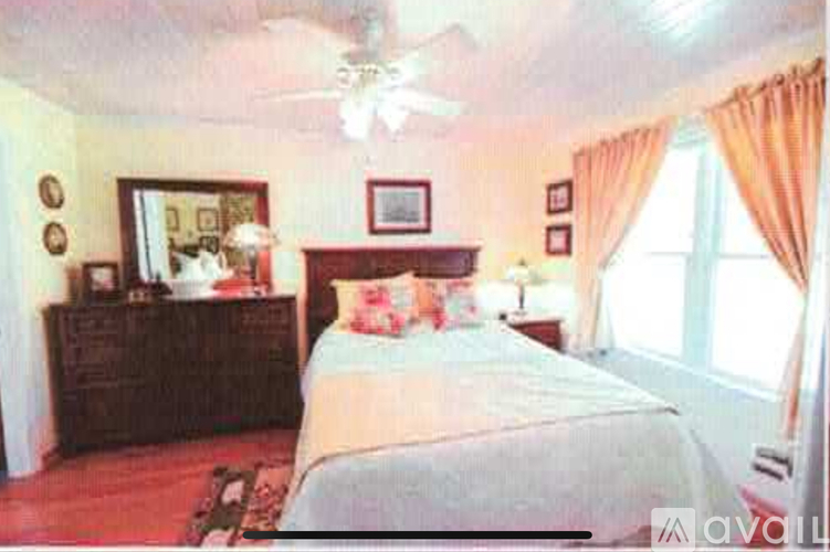 A bedroom with a bed, dresser, and window.