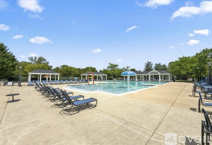 A pool area with sun loungers and a clear blue sky.