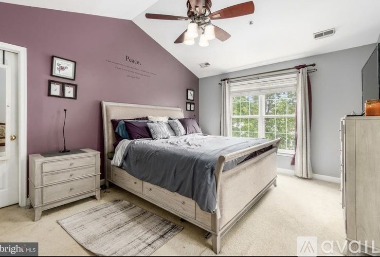 A bedroom with a bed, dresser, and ceiling fan.