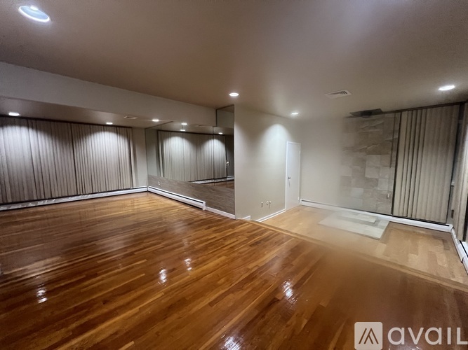 A spacious room with wooden flooring and a white ceiling.