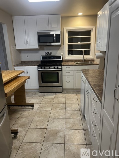 A kitchen with white cabinets and a tile floor.