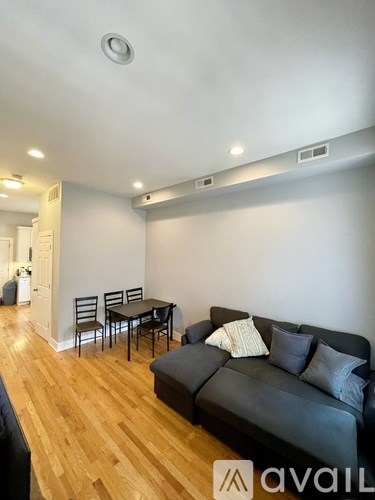 A living room with a black couch and wooden floors.
