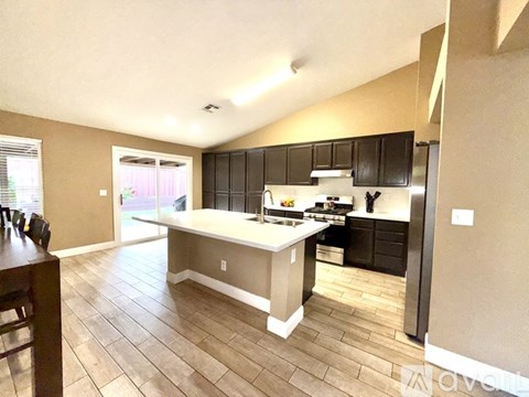 A kitchen with a center island and black cabinets.