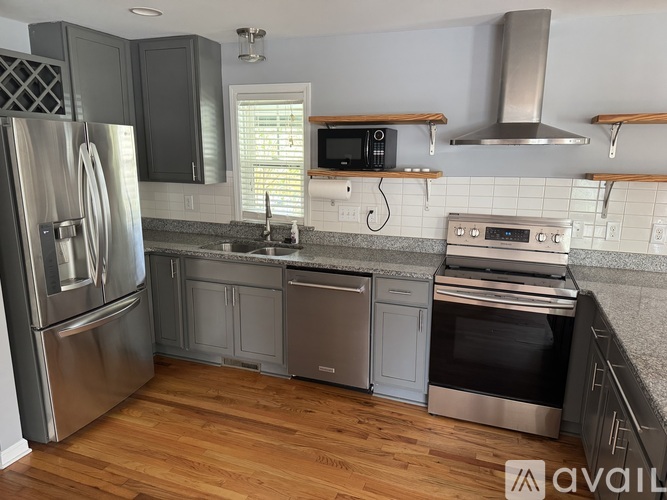 A kitchen with a stainless steel refrigerator and wooden floors.