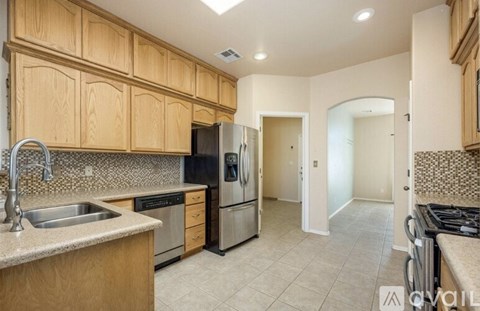 A kitchen with wooden cabinets and a stainless steel refrigerator.