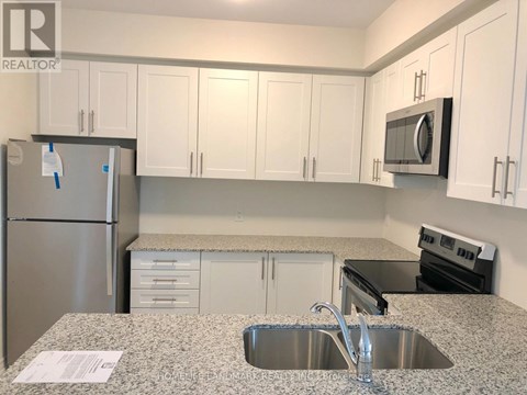 A kitchen with a sink, refrigerator, and microwave.