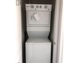 A white Whirlpool dishwasher and dryer are stacked in a small space.
