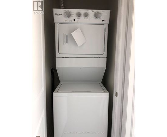A white Whirlpool dishwasher and dryer are stacked in a small space.