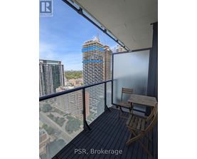 A balcony with a table and chairs overlooking a cityscape under construction.