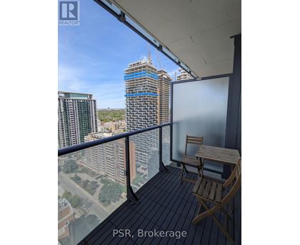 A balcony with a table and chairs overlooking a cityscape under construction.