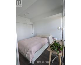 A bedroom with a bed, chair, and plant.