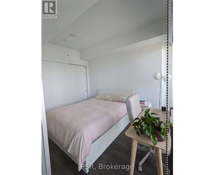 A bedroom with a bed, chair, and plant.