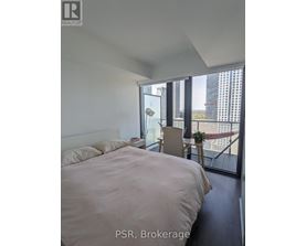 A bedroom with a large bed and a balcony overlooking a cityscape.