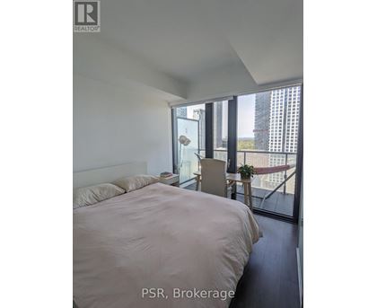 A bedroom with a large bed and a balcony overlooking a cityscape.