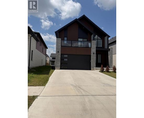 A modern house with a large driveway in front.