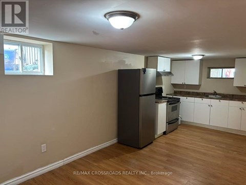 A kitchen with a refrigerator, oven, and cabinets.