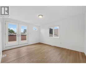 A room with a white wall and a window with a view of a building.