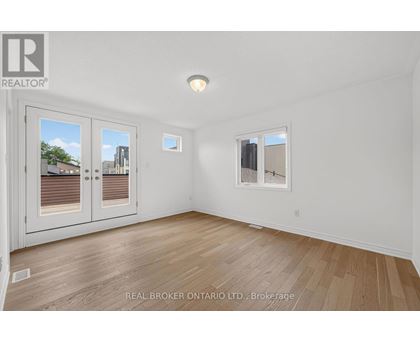 A room with a white wall and a window with a view of a building.