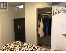 A bedroom with a black and white patterned bedspread and a black wardrobe.