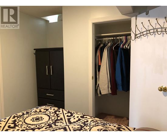 A bedroom with a black and white patterned bedspread and a black wardrobe.