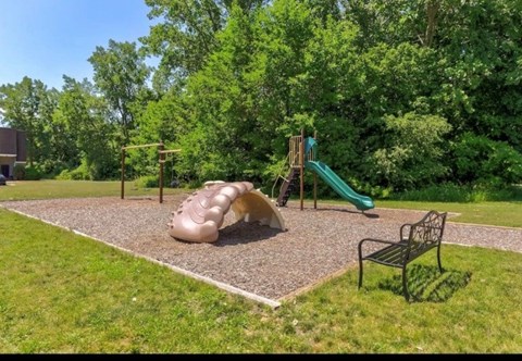 A playground with a slide, a climbing frame and a bench.
