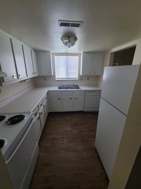 A kitchen with white cabinets and a white fridge.