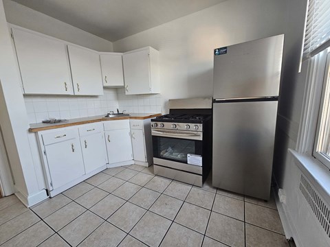 A kitchen with white cabinets and a stainless steel refrigerator.