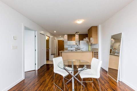 A dining room with a glass table and white chairs.