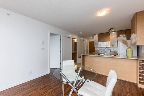 A modern kitchen with a glass table and white chairs.