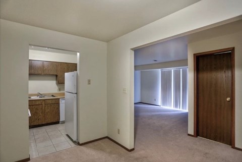 A kitchen with a refrigerator and wooden cabinets is visible through a doorway.