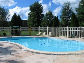A pool surrounded by a white fence and trees.