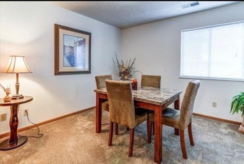 A dining room with a table, chairs, and a painting on the wall.