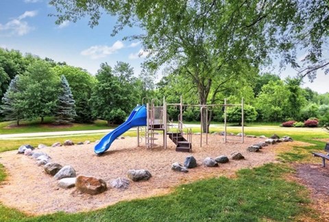 A playground with a blue slide and a wooden swing set.