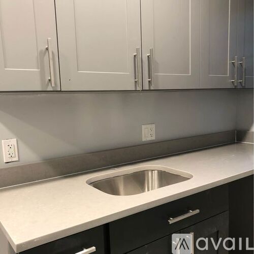 A kitchen with a stainless steel sink and white cabinets.