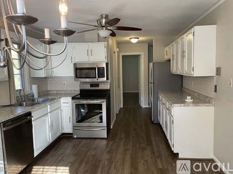 A kitchen with white cabinets and a wooden floor.