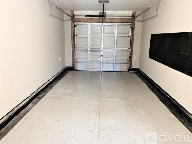 A spacious garage with a large metal door and a blackboard on the wall.