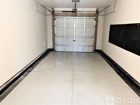A spacious garage with a large metal door and a blackboard on the wall.