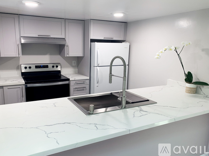 A modern kitchen with a stainless steel refrigerator and a marble countertop.