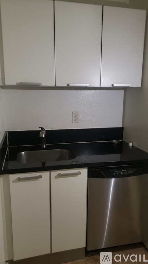 A kitchen with a stainless steel dishwasher and white cabinets.