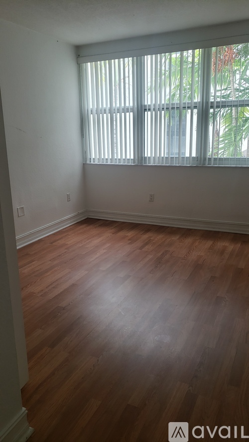 A room with wooden floors and a window with blinds.