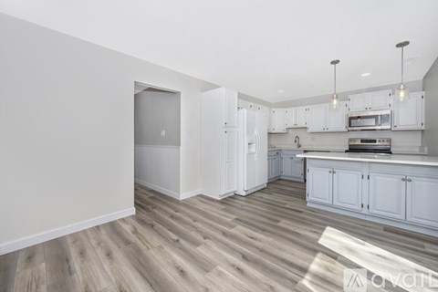 A kitchen with white cabinets and a wooden floor.