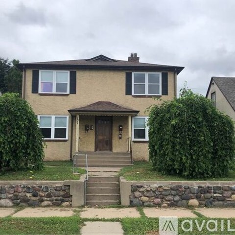 A house with a brown door and a stone wall in front.