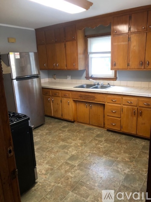 A kitchen with wooden cabinets and a tiled floor.