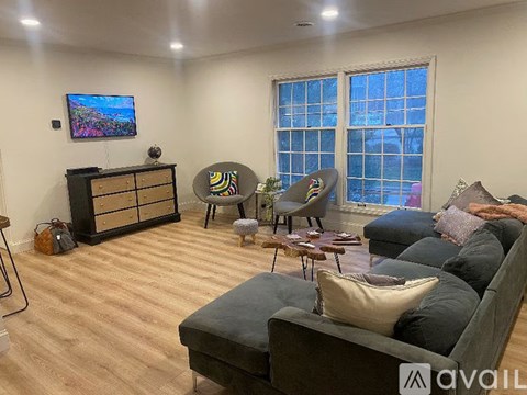 A living room with a grey couch, a black cabinet, and a television on the wall.