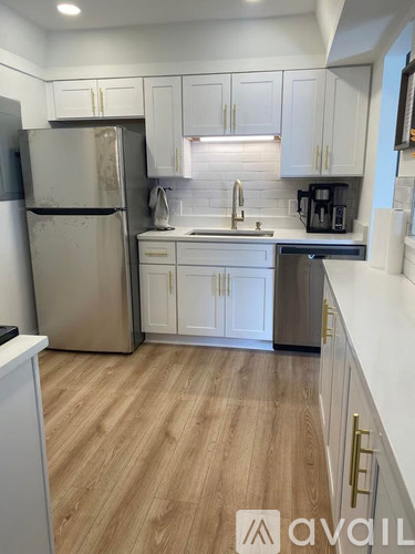 A kitchen with white cabinets and a wooden floor.